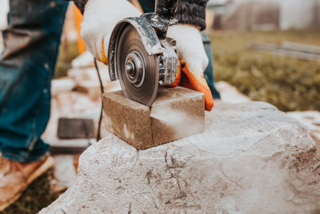 Diamond blade grinder efficiently cuts concrete blocks for stone tile sidewalk installation.